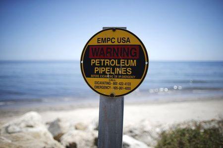 A sign warns of petroleum pipelines next to an oil slick along the coast of Refugio State Beach in Goleta